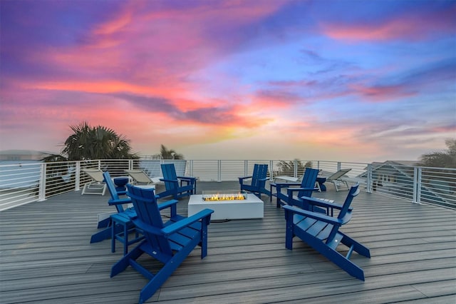 deck at dusk featuring an outdoor fire pit and a water view