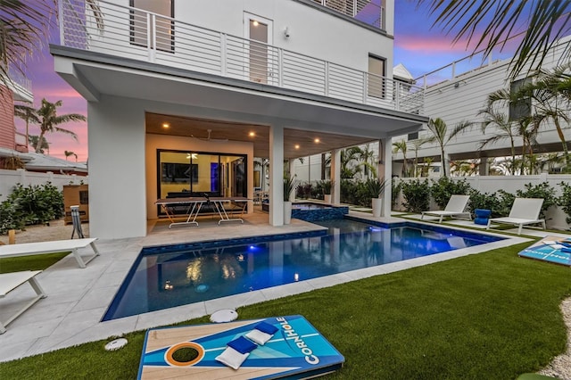 pool at dusk with a patio area, fence, a fenced in pool, and a yard