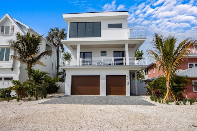 view of front of house featuring driveway, an attached garage, a balcony, and stucco siding