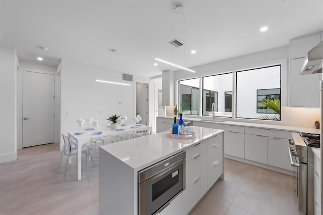 kitchen featuring a center island, light countertops, stainless steel microwave, white cabinetry, and modern cabinets