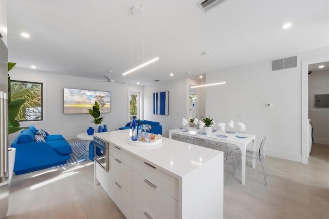 kitchen featuring white cabinets, modern cabinets, a kitchen island, light countertops, and pendant lighting