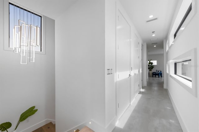 hall featuring concrete flooring, recessed lighting, visible vents, and baseboards