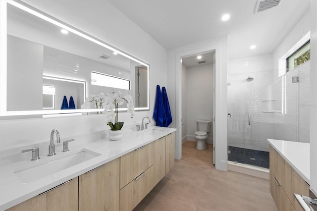 full bathroom featuring double vanity, visible vents, toilet, a stall shower, and a sink