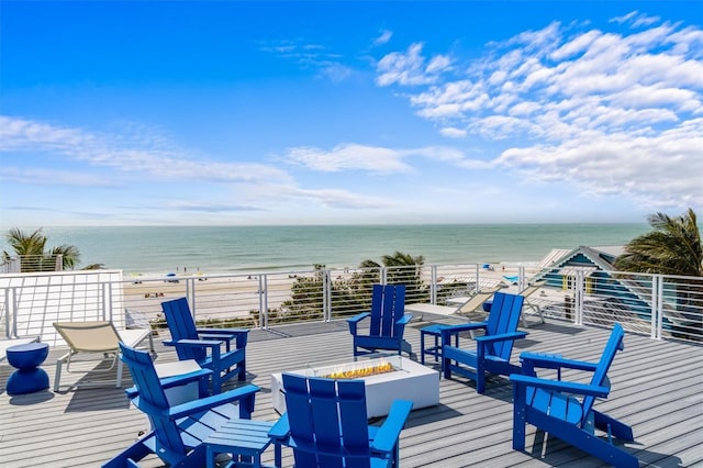 deck with a water view, a fire pit, and a view of the beach