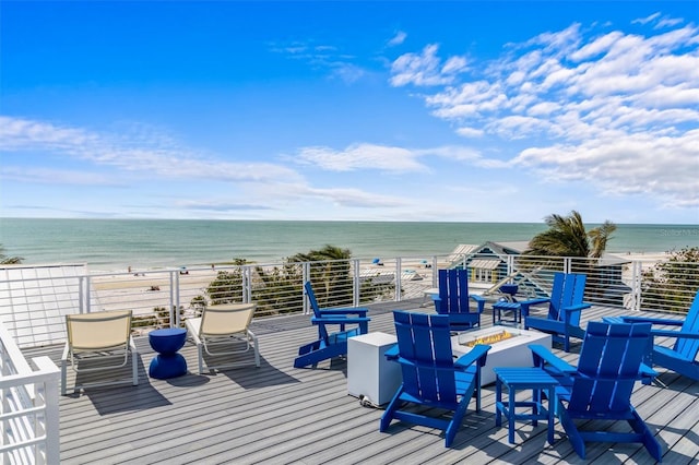 deck featuring a fire pit, a water view, and a view of the beach