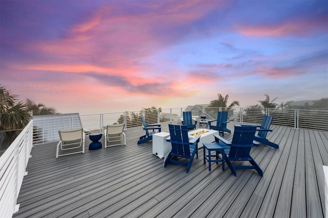 deck at dusk with a fire pit and a water view