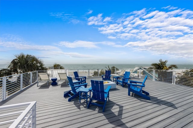 deck featuring a view of the beach, a water view, and a fire pit