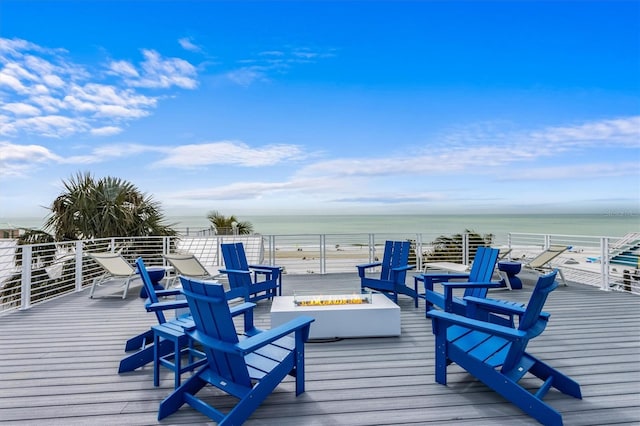 deck with a water view, a fire pit, and a view of the beach