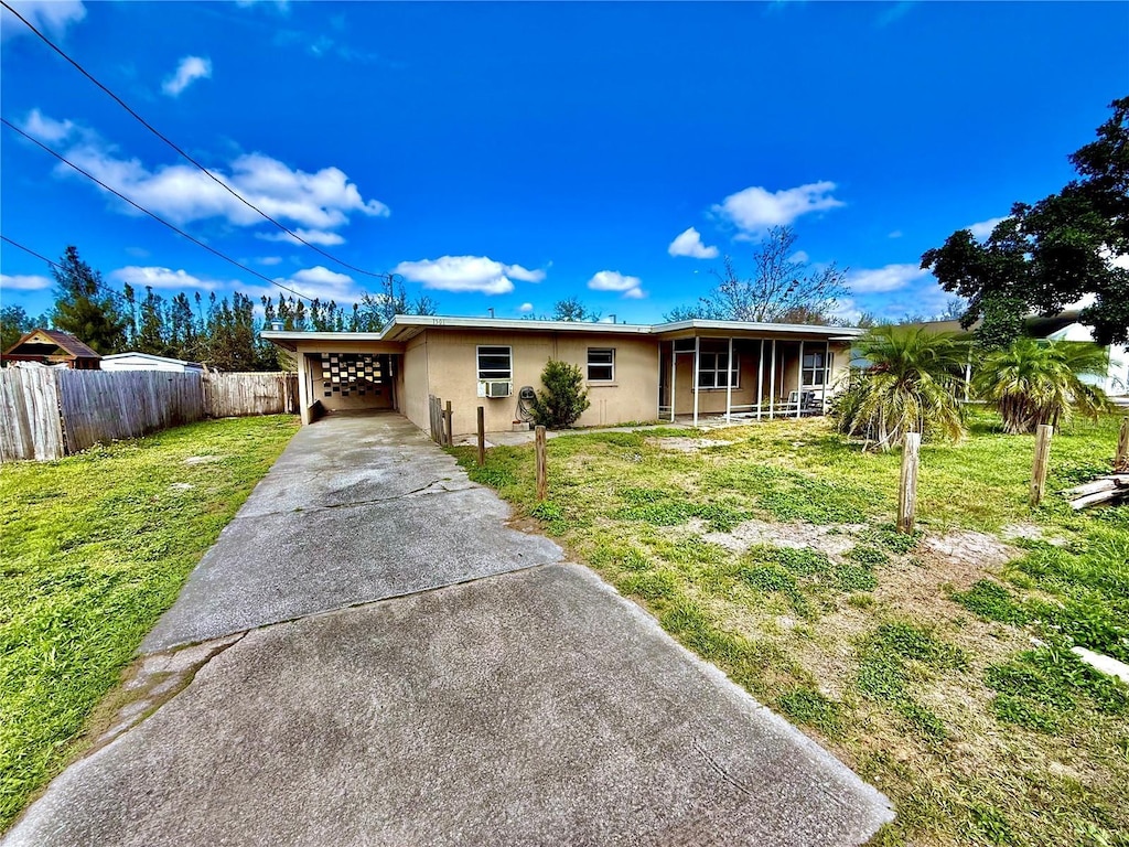 single story home featuring driveway, an attached carport, fence, a front yard, and stucco siding