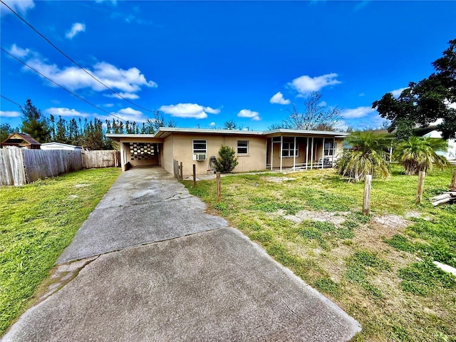 single story home featuring driveway, an attached carport, fence, a front yard, and stucco siding