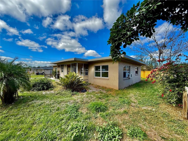 rear view of property with a yard, cooling unit, fence, and stucco siding