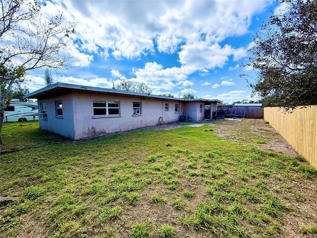 rear view of house featuring a fenced backyard, a yard, and stucco siding