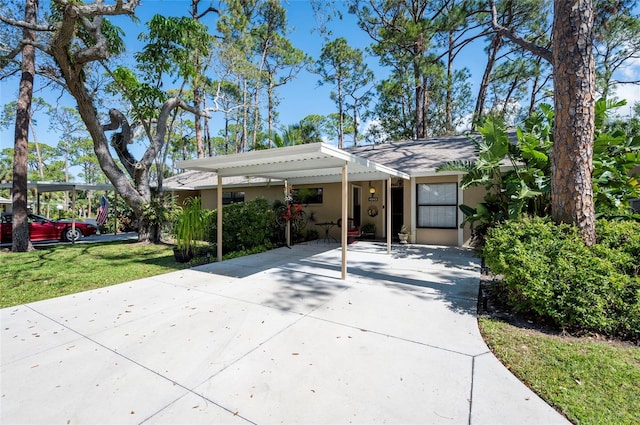 view of front of house with a carport, a front yard, driveway, and stucco siding