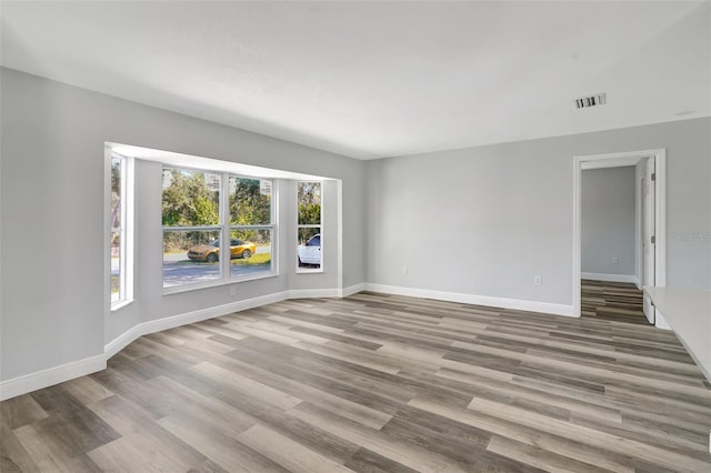 spare room featuring light wood-type flooring, visible vents, and baseboards