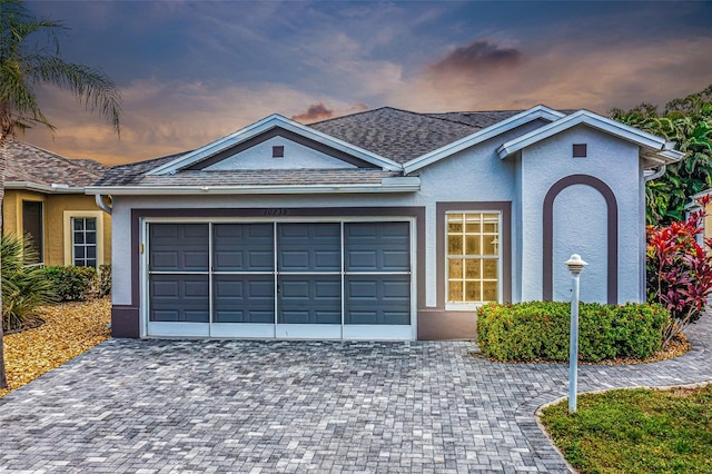 ranch-style house with an attached garage, decorative driveway, and stucco siding