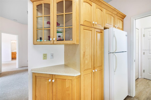 kitchen with light colored carpet, glass insert cabinets, light countertops, and freestanding refrigerator