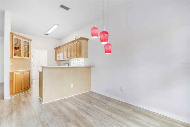 kitchen featuring white microwave, a peninsula, visible vents, light wood-style floors, and light countertops