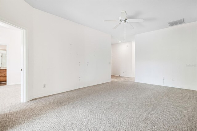 unfurnished room with a ceiling fan, light carpet, visible vents, and baseboards