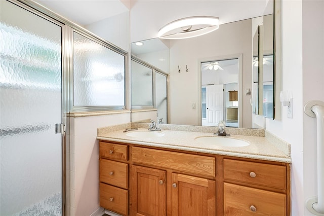 bathroom featuring double vanity, a stall shower, and a sink