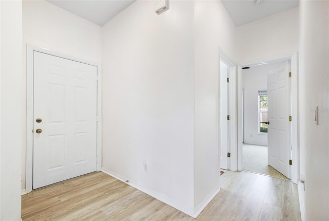 corridor featuring light wood-style flooring and baseboards