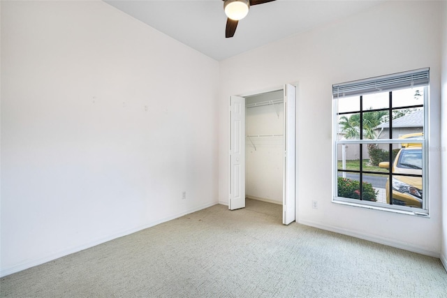 unfurnished bedroom featuring ceiling fan, baseboards, a closet, and light colored carpet