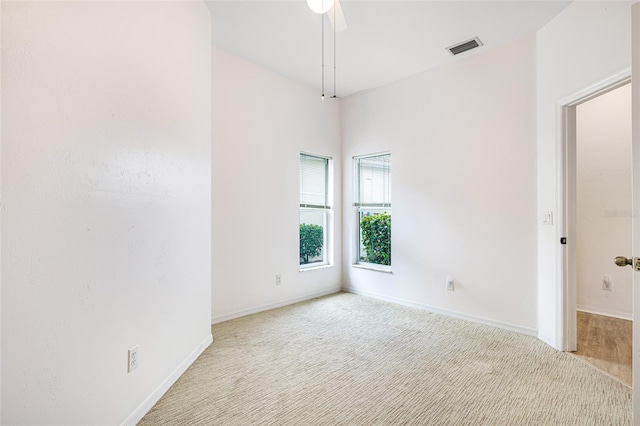 unfurnished room featuring light colored carpet, visible vents, ceiling fan, and baseboards