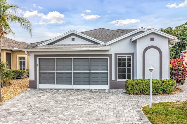 ranch-style home featuring a garage, roof with shingles, decorative driveway, and stucco siding