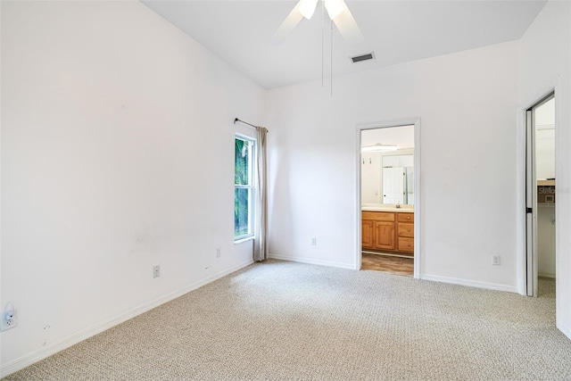 unfurnished bedroom with visible vents, a spacious closet, ensuite bathroom, light carpet, and baseboards