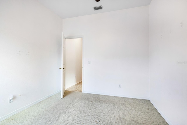 spare room with baseboards, visible vents, and light colored carpet