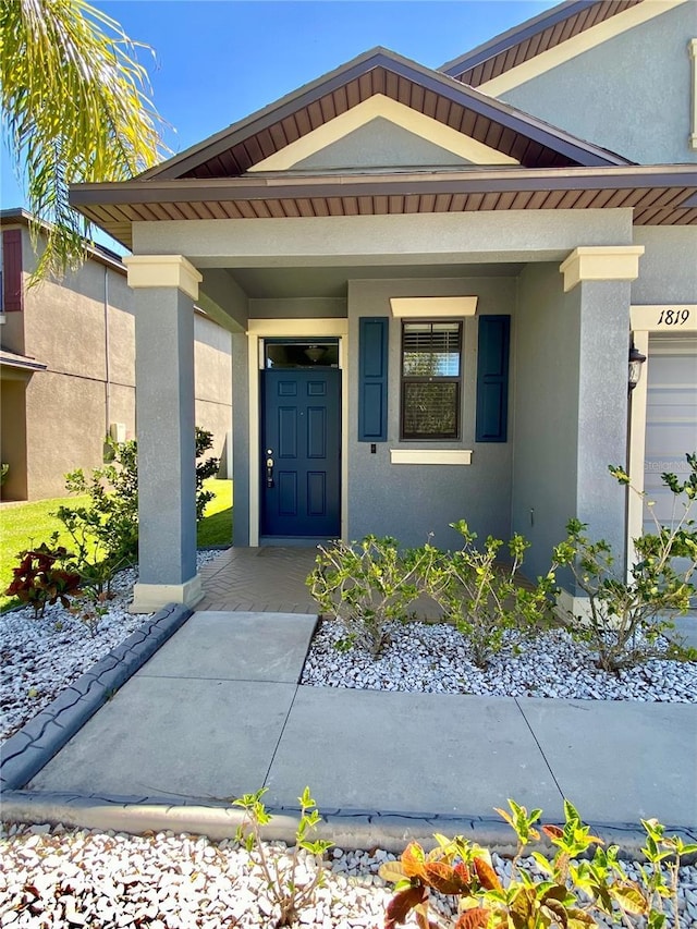 property entrance with covered porch and stucco siding