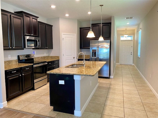 kitchen featuring stainless steel appliances, light tile patterned flooring, a sink, and light stone countertops