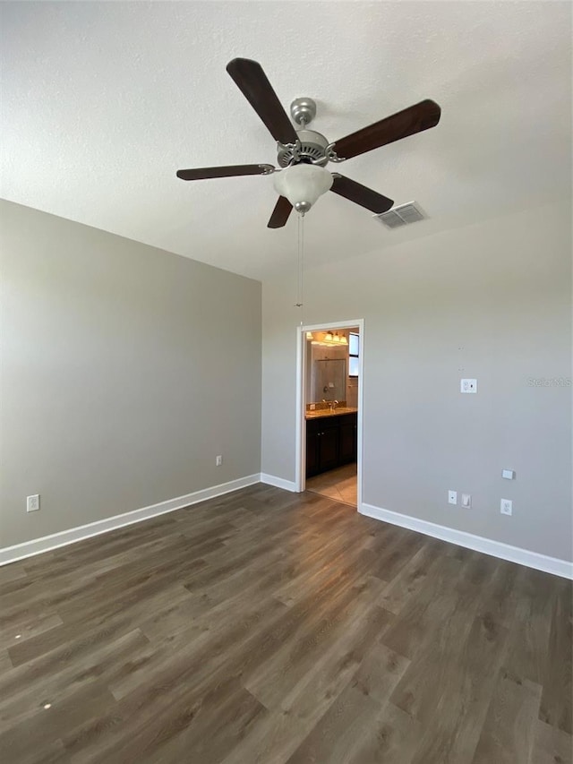 unfurnished room featuring baseboards, visible vents, ceiling fan, dark wood-type flooring, and a textured ceiling