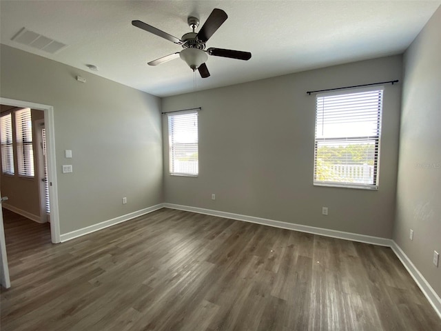 spare room featuring baseboards, visible vents, dark wood finished floors, and a ceiling fan