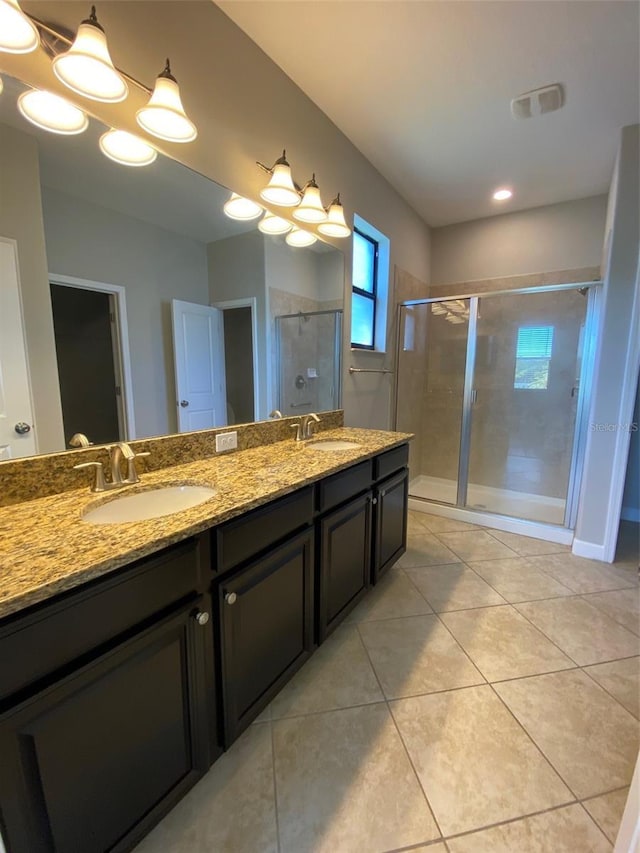 full bathroom featuring double vanity, a stall shower, tile patterned flooring, and a sink