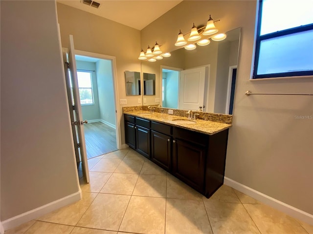 bathroom featuring double vanity, tile patterned flooring, a sink, and baseboards