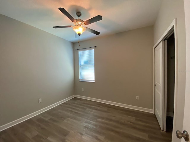 unfurnished bedroom featuring a ceiling fan, a closet, dark wood finished floors, and baseboards