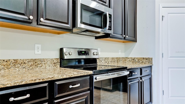 kitchen with dark cabinets, appliances with stainless steel finishes, and light stone countertops
