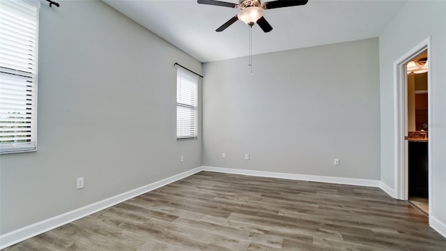 spare room featuring baseboards, ceiling fan, and wood finished floors
