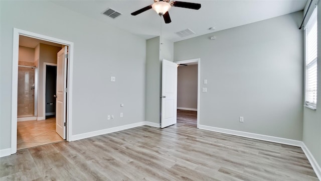 unfurnished bedroom featuring baseboards, visible vents, ensuite bathroom, and light wood finished floors