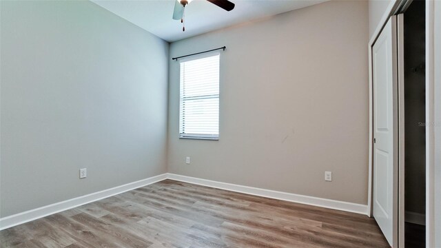 unfurnished bedroom with baseboards, a ceiling fan, a closet, and wood finished floors