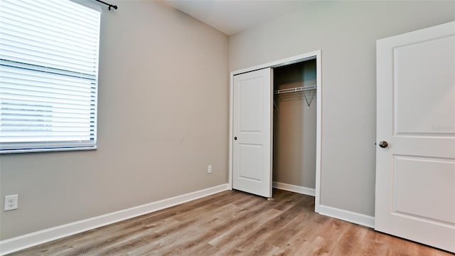 unfurnished bedroom featuring baseboards, a closet, and light wood-style flooring