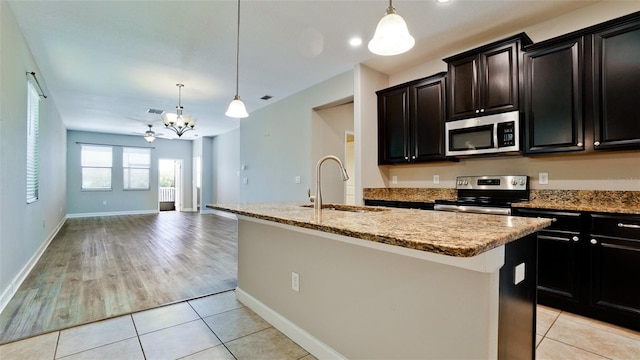 kitchen featuring an inviting chandelier, pendant lighting, a center island with sink, a sink, and stainless steel appliances