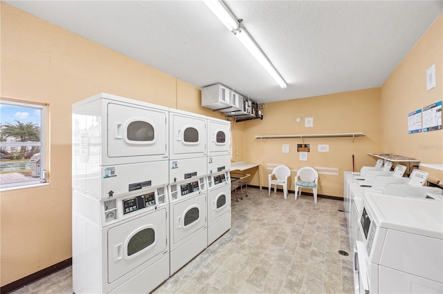 community laundry room with baseboards, stacked washer and clothes dryer, a textured ceiling, and washing machine and clothes dryer