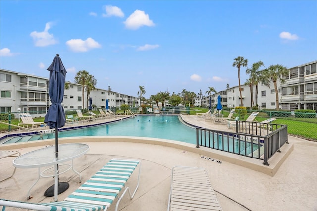 community pool featuring fence, a patio, and a residential view