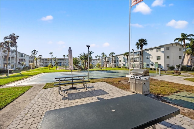view of community featuring shuffleboard, a lawn, and a residential view