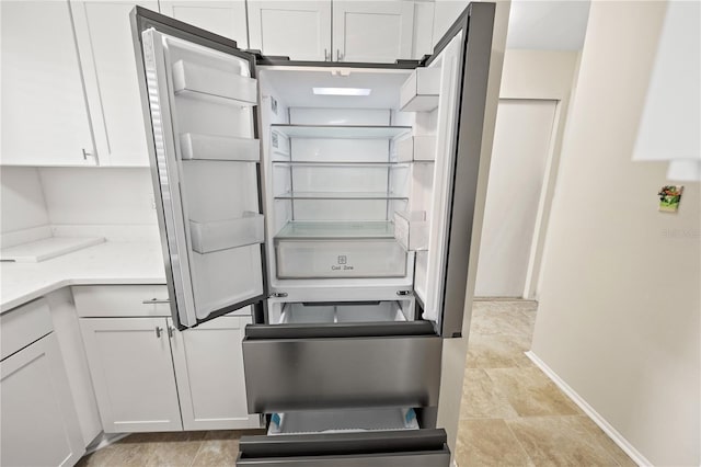 kitchen with light countertops, fridge, and white cabinetry