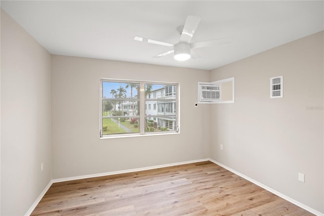 empty room with a ceiling fan, visible vents, baseboards, an AC wall unit, and light wood-style flooring
