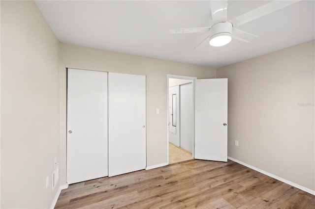 unfurnished bedroom featuring baseboards, a ceiling fan, a closet, and light wood-style flooring