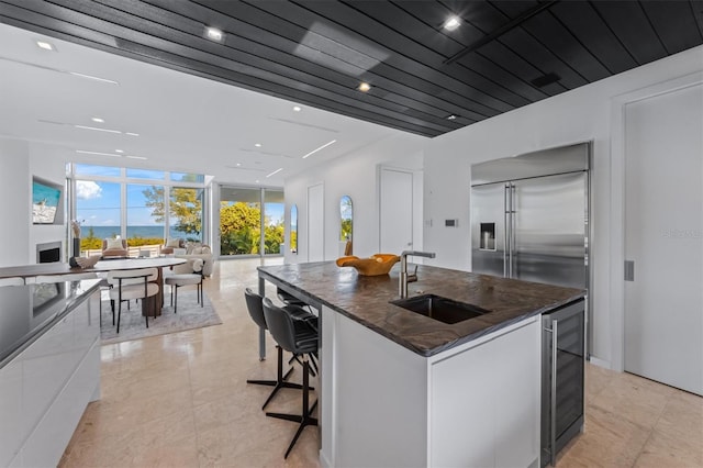 kitchen featuring beverage cooler, modern cabinets, a sink, and a center island with sink