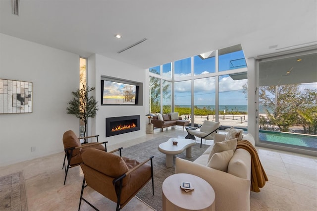 living area featuring visible vents, floor to ceiling windows, and a lit fireplace